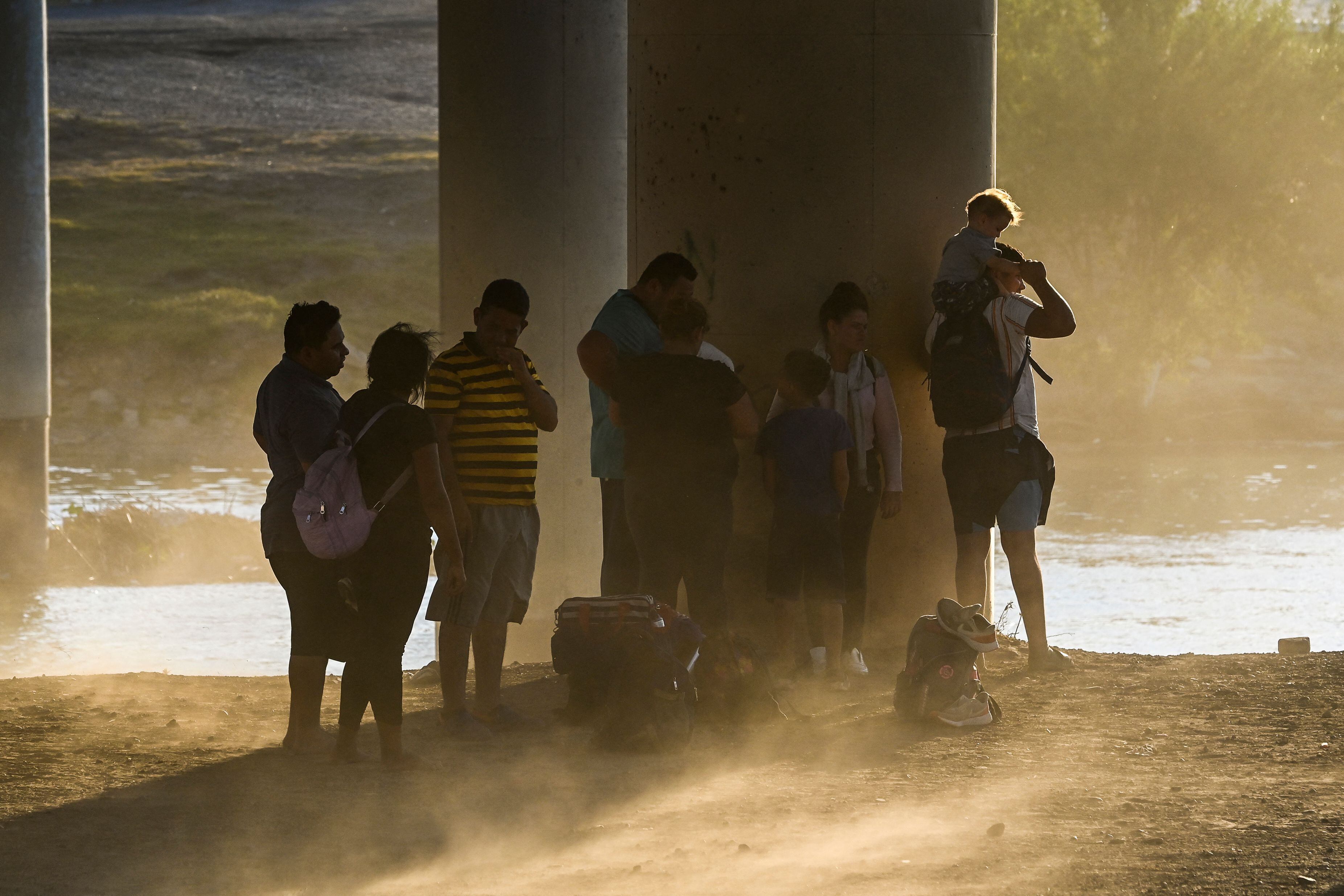 Una familia migrante de Venezuela espera, en medio de una tormenta de arena, a ser aprehendida por la Policía de Fronteras en Eagle Pass, en Texas, cerca de la frontera con México.