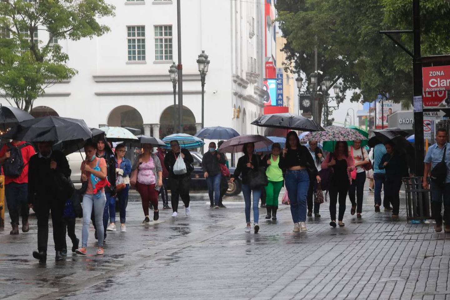 Cerca del parque de las Garantías Sociales, los josefinos tuvieron que abrir sombrillas y paraguas la tarde de este lunes. Se prevén tardes lluviosas el resto de la semana. Foto: Rafael Pacheco..