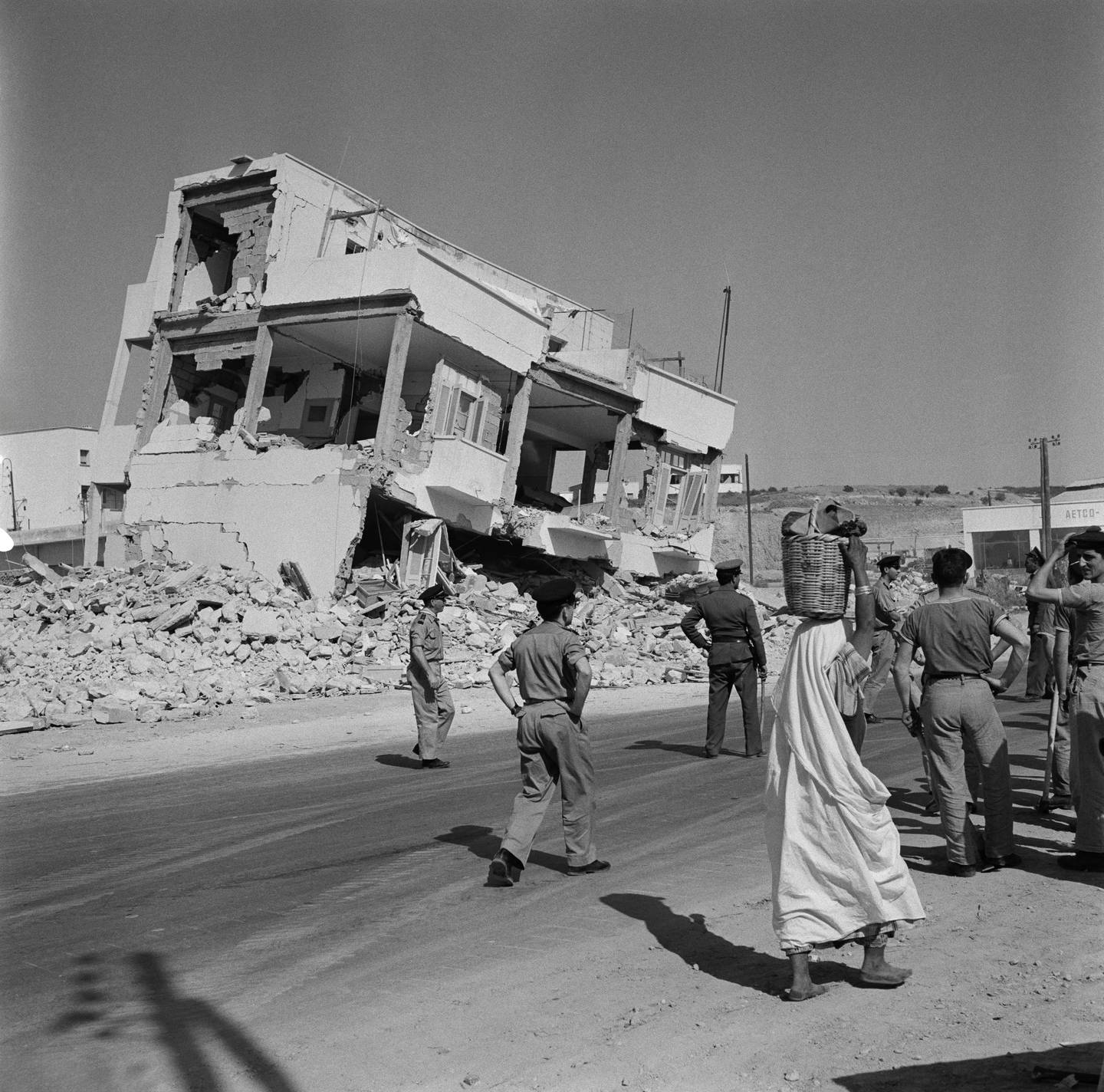 Civiles y soldados caminan frente a uno de los edificios destruídos tras el sismo en Marruecos.