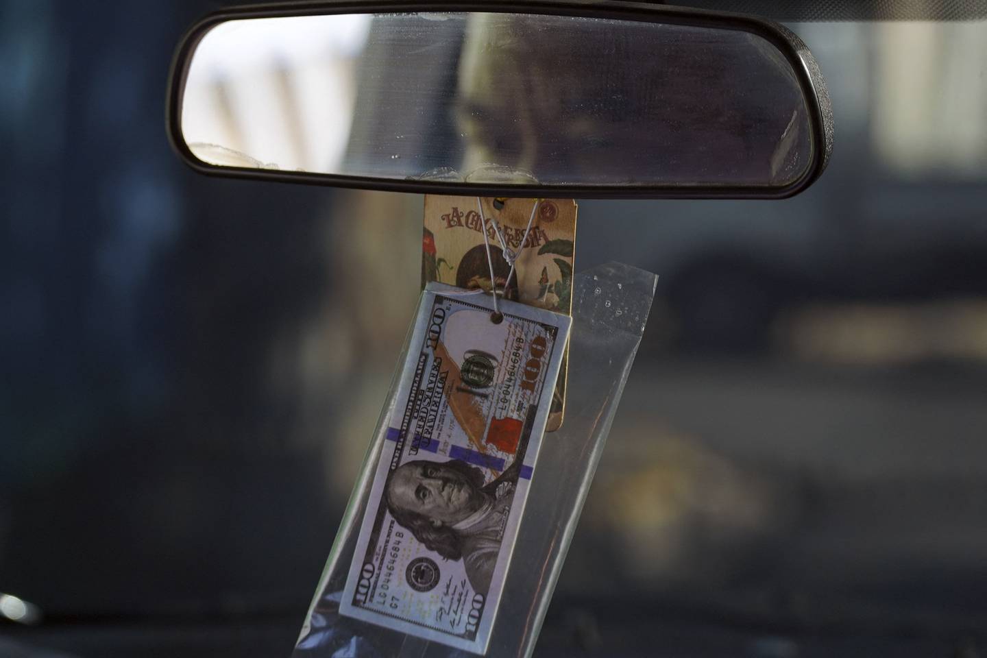 Un taxista lleva en su vehículo un adorno alusivo a dólares estadounidenses en San Salvador