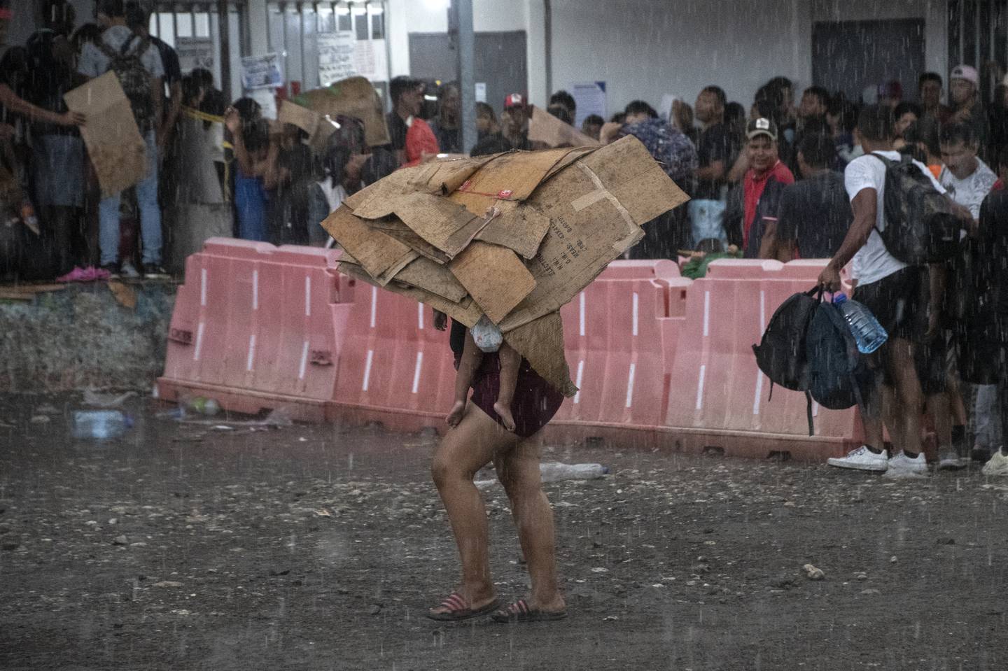 Una mujer migrante y su bebé se protegen de la lluvia con cartones en un refugio improvisado en Paso Canoas, a unos 300 km al sur de San José, en la provincia de Puntarenas.
