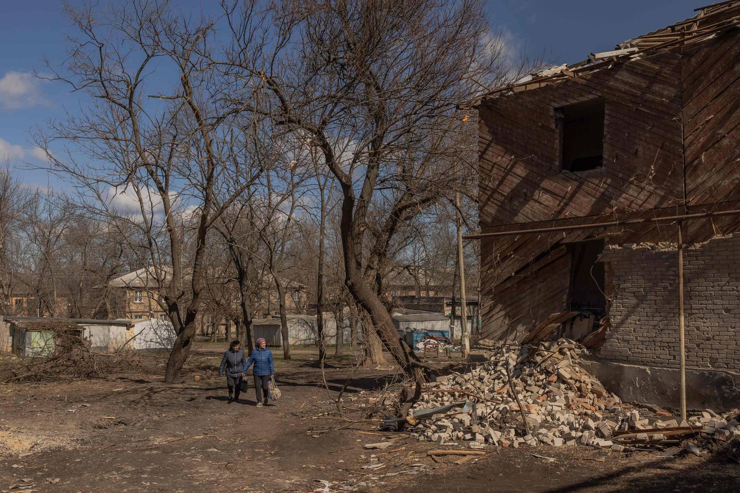 Los peatones pasan junto a un edificio residencial que resultó gravemente dañado tras un bombardeo este sábado, en la ciudad de Mykolaivka, cerca de Slaviansk, en el norte de la región de Donetsk, al este de Ucrania, en medio de la invasión rusa de Ucrania. (Foto: Román PILIPEY / AFP)