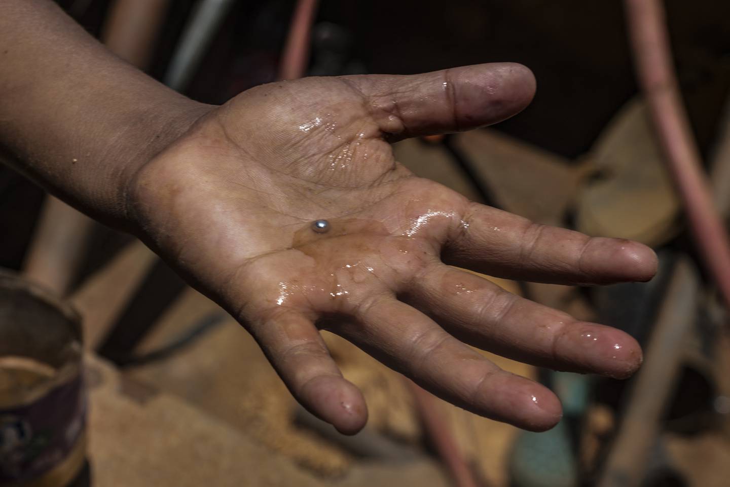 Un niño minero venezolano muestra una bola de mercurio que se utiliza diariamente para separar el oro que se encuentra entre charcos de lodo en una mina a cielo abierto para luego ser procesado manualmente en un molino en El Callao