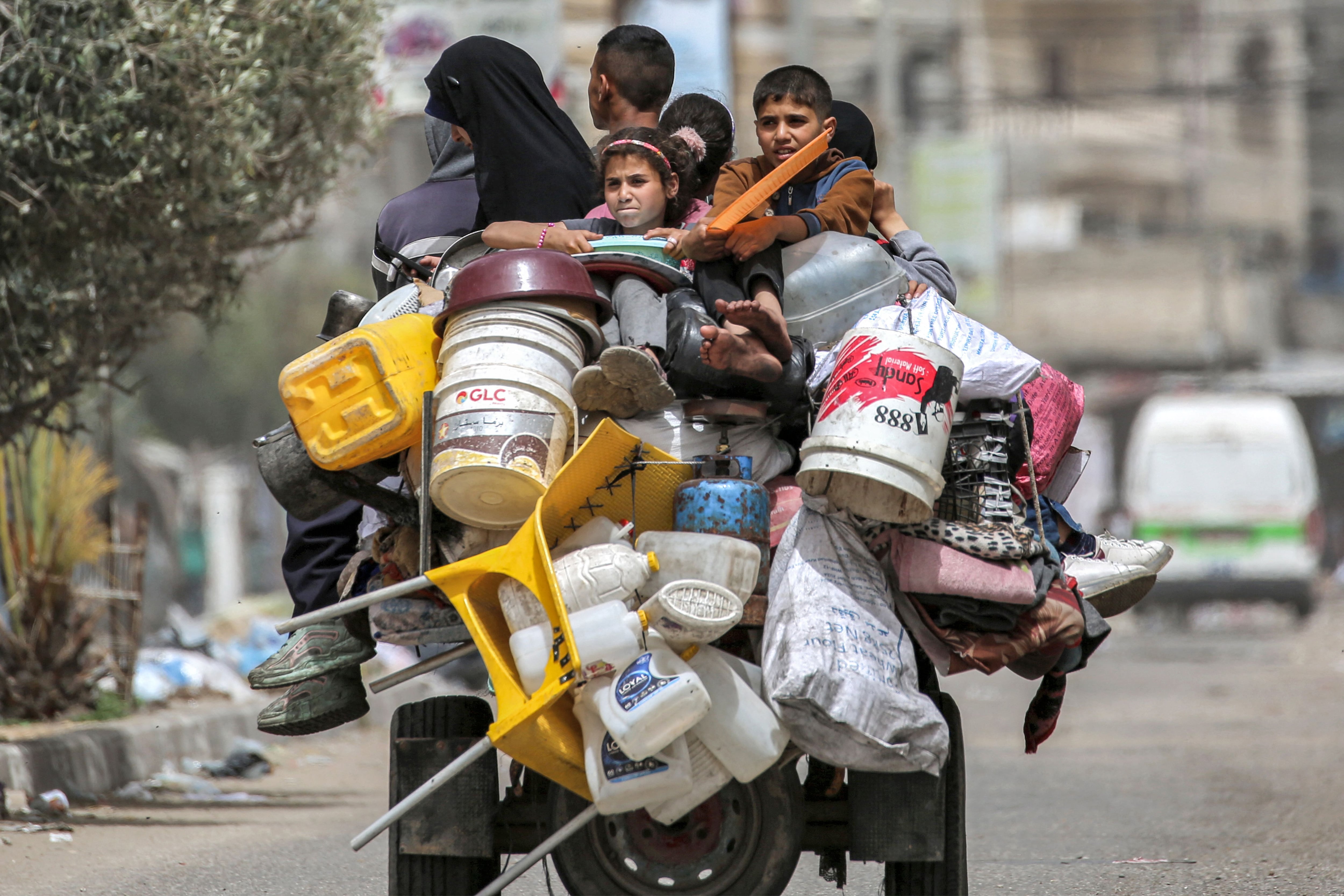 Un hombre, una mujer y niños viajan en la parte trasera de un triciclo cargado con pertenencias y otros artículos mientras huyen con destino a Khan Yunis, en Rafah, Gaza. Foto: AFP