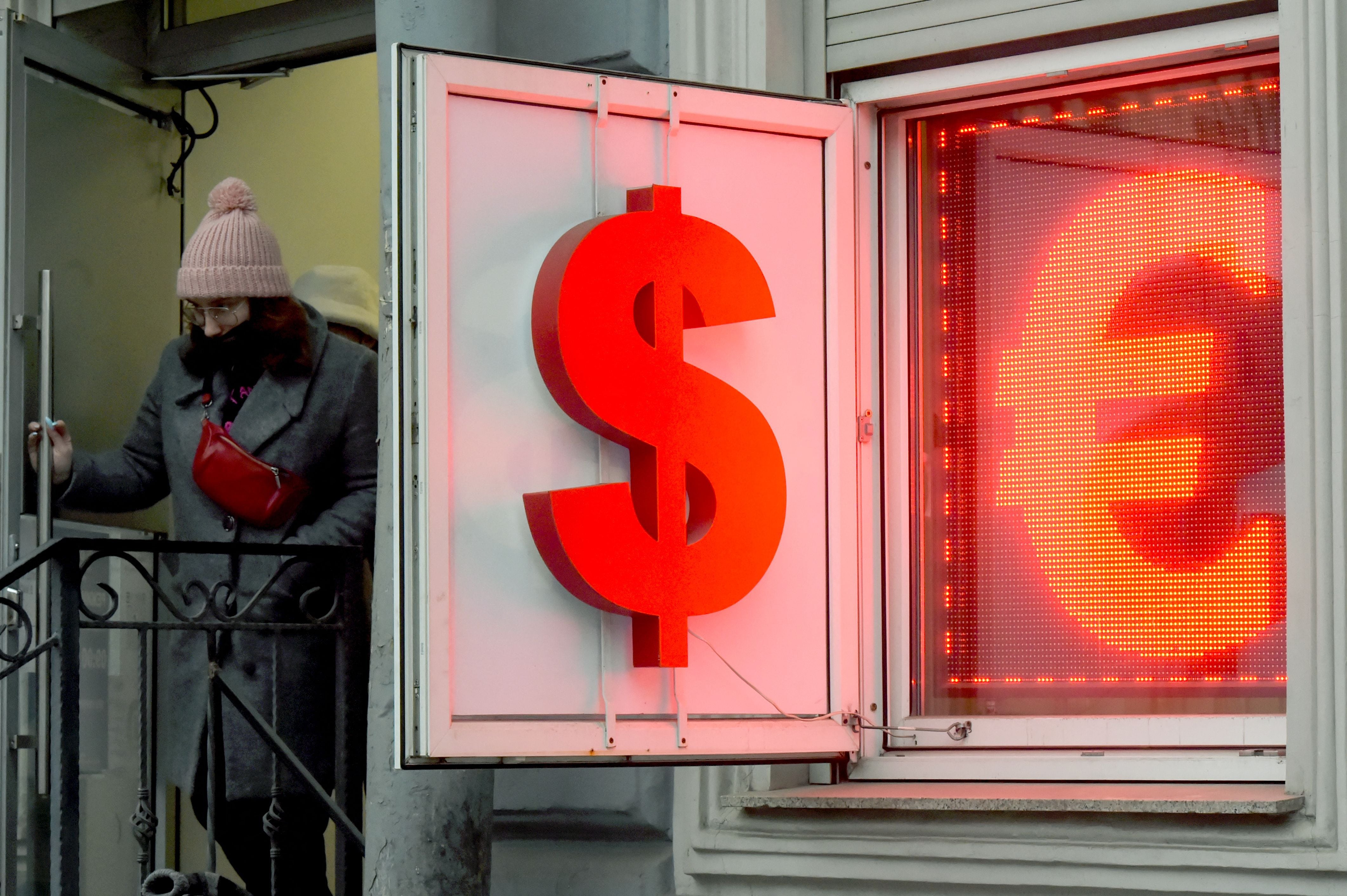 Una mujer sale de una oficina de cambio de moneda que muestra el dólar estadounidense y el euro en San Petersburgo.