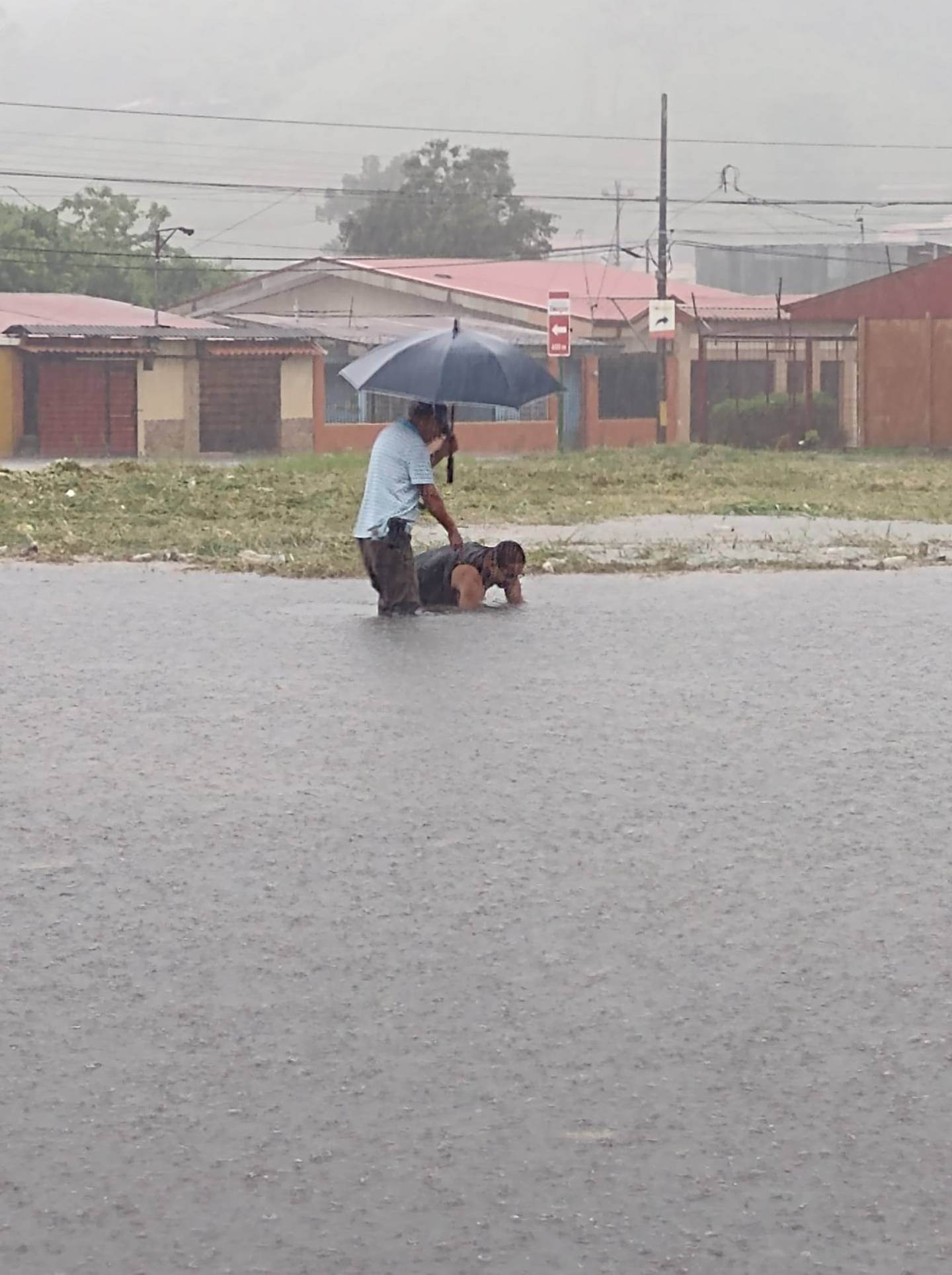 Vecinos de urbanización Las Catalinas en El Tejar, de El Guarco, Cartago, trataban de desatorar una alcantarilla en medio de las fuertes lluvias de este martes. Foto: Cortesía.