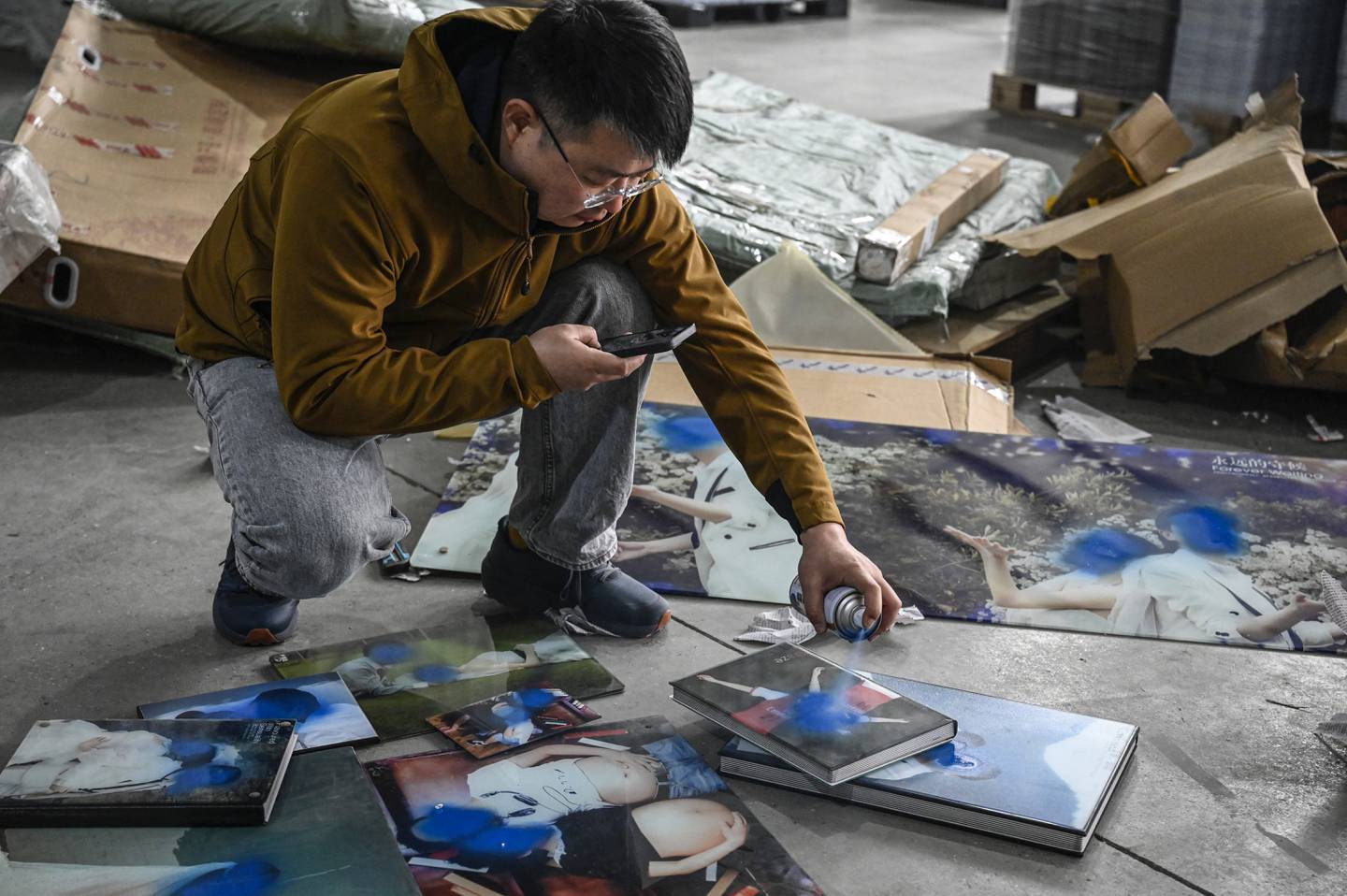 Trabajador Liu Wei rociando pintura sobre fotografías de bodas no deseadas de clientes en un almacén en Langfang, en la provincia de Hebei, en el norte de China.