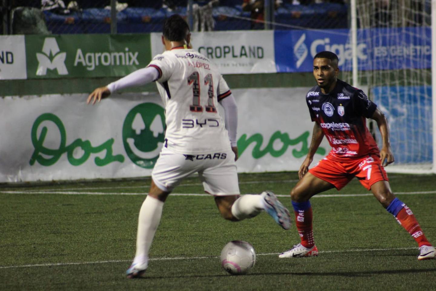 Alex López intenta superar la marca de César Yanis en el partido entre San Carlos y Liga Deportiva Alajuelense.