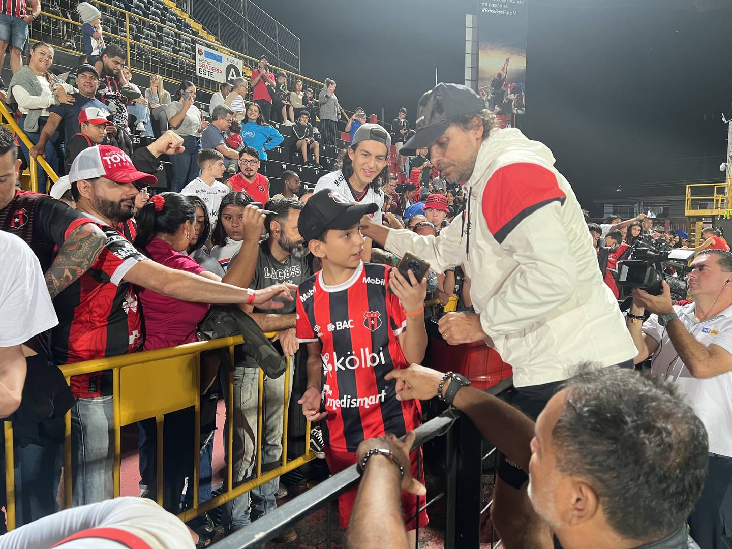 Andrés Carevic se subió a una malla para tomarse fotografías con los aficionados de Liga Deportiva Alajuelense que querían un recuerdo con él.