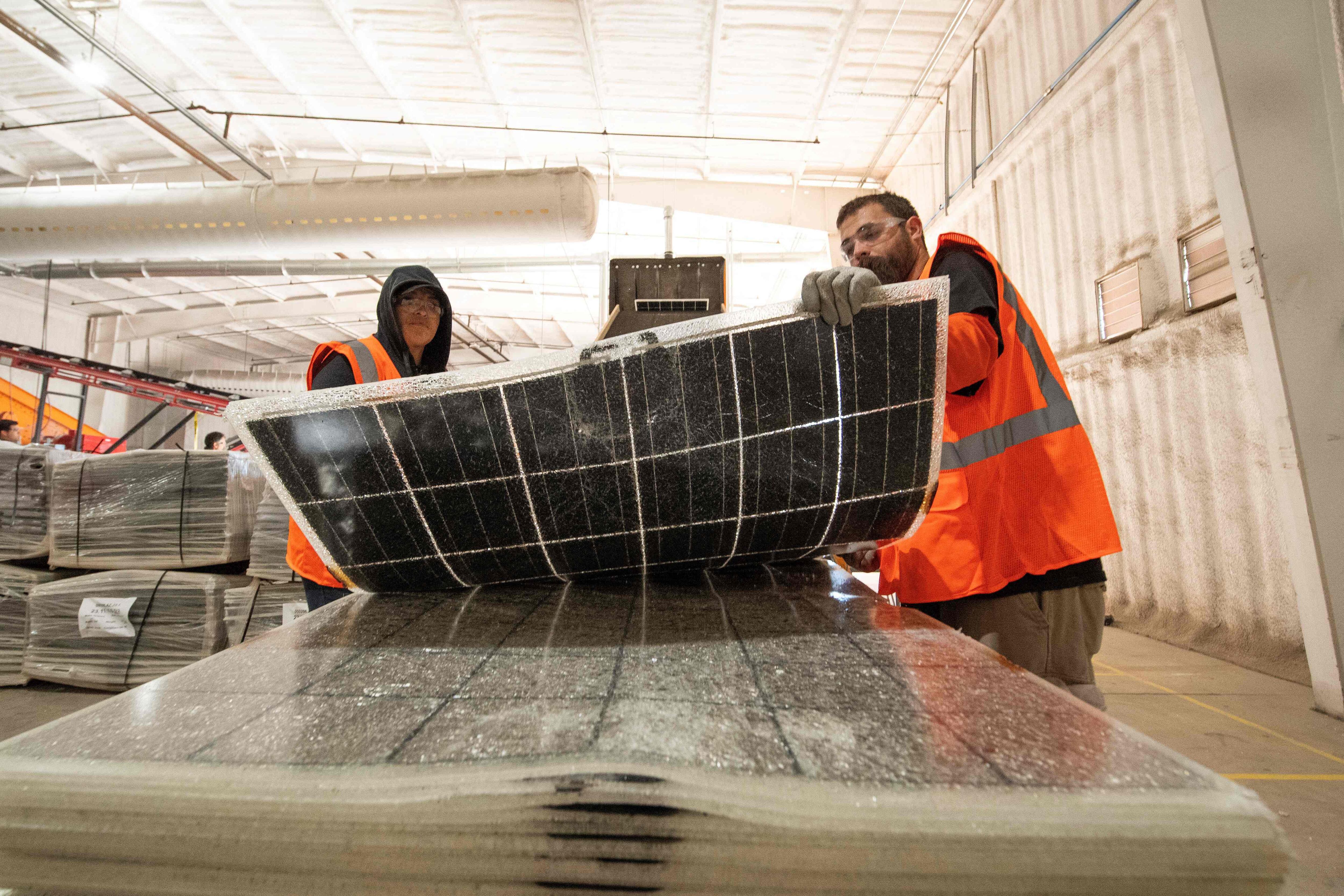 Trabajadores empujan paneles solares dañados hacia una máquina para reciclarlos en la planta We Recycle Solar en Yuma, Arizona. Fotografía: