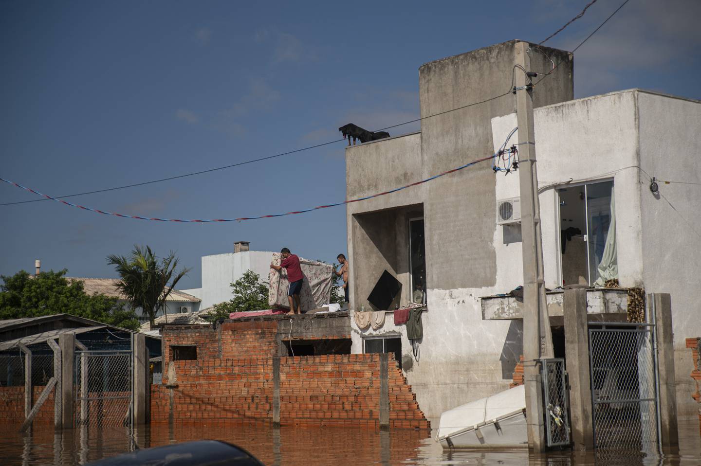 Dos hombres dejaron secar al sol sus pertenencias recuperadas de su casa inundada en la ciudad de Eldorado do Sul, estado de Rio Grande do Sul, Brasil, el 9 de mayo de 2024. (Foto de Carlos FABAL/AFP)