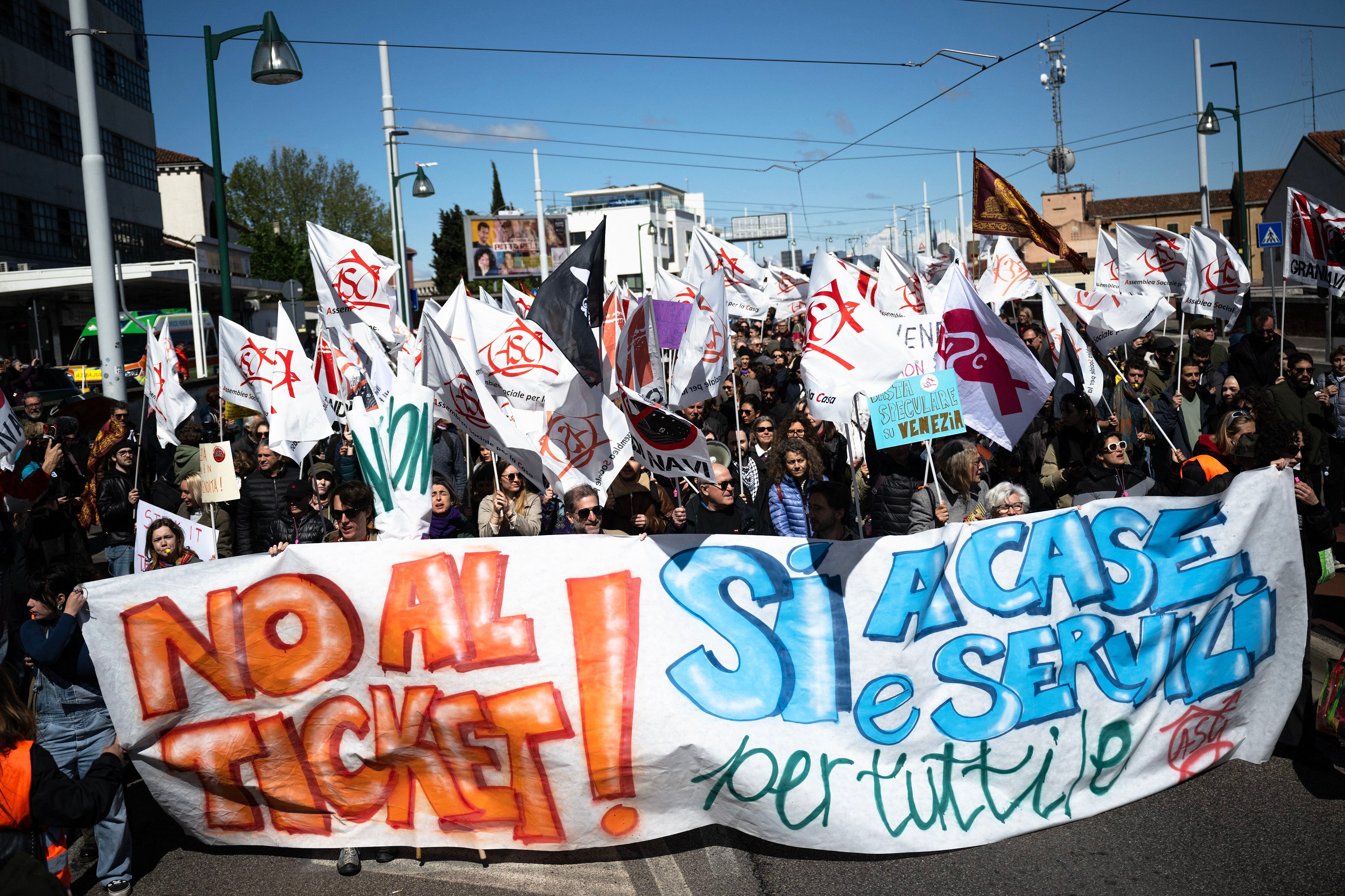 Los manifestantes sostienen una pancarta que dice 'No al billete, sí a las casas y servicios para todos' mientras participan en una manifestación contra la nueva 'Tarifa de Acceso a Venecia'