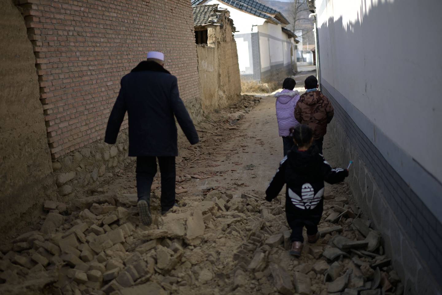 La gente camina entre los escombros después de un terremoto en la aldea de Gaoli en el condado de Jishishan, en la provincia de Gansu, en el noroeste de China, esto sucedió el pasado mes de diciembre.. Los sobrevivientes del terremoto más mortífero de China en años se apiñaron en tiendas de campaña de ayuda el miércoles después de que las temperaturas nocturnas cayeran muy por debajo de cero, con el número de muertos aumentando. al 131. (Foto de PEDRO PARDO / AFP)