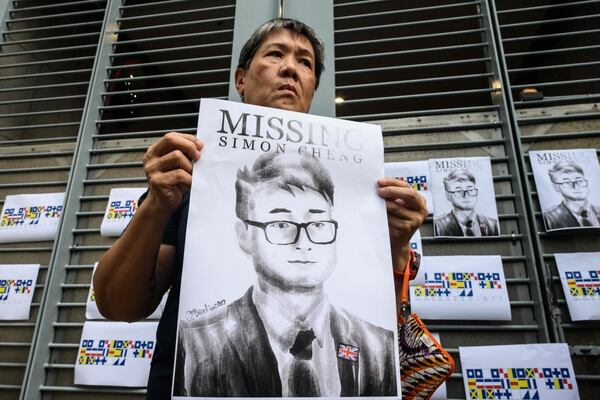 An activist holds an illustration of Simon Cheng during a gathering outside the British Consulate-General building in Hong Kong on August 21, 2019, following reports that the Hong Kong consulate employee had been detained by mainland Chinese authorities on his way back to the city. - An employee of Britain's consulate in Hong Kong who went missing earlier this month is being held in China, Beijing confirmed on August 21. (Photo by Anthony WALLACE / AFP)