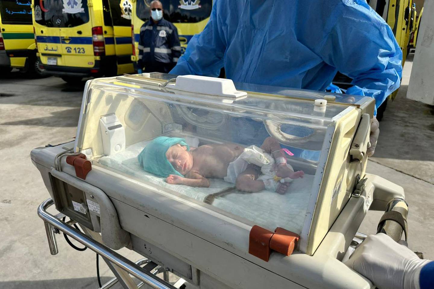 Médicos egipcios llevan a un bebé palestino prematuro evacuado de Gaza a una ambulancia en el lado egipcio del cruce fronterizo de Rafah con la Franja de Gaza en medio de las batallas en curso entre Israel y el grupo militante Hamas.