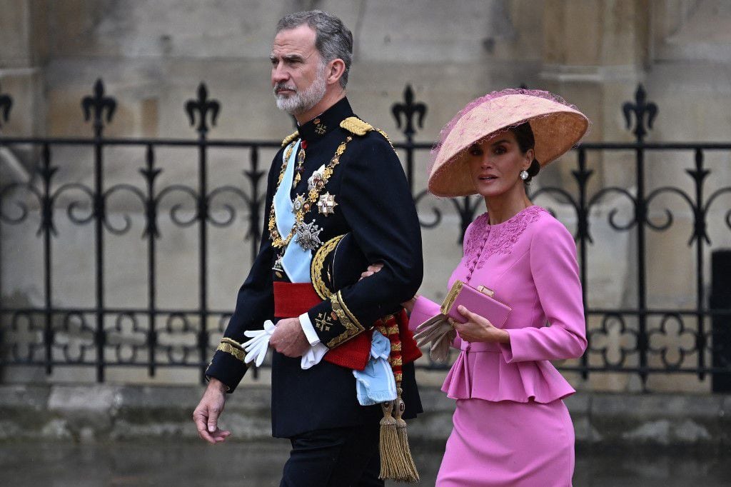 La esposa del rey Felipe VI, Letizia, lució un conjunto de dos piezas de Carolina Herrera en color rosa y un sombrero oriental tipo kasa. Sobre el sombrero se observa una red rosa que hace combinación con sus tacones y cartera. 