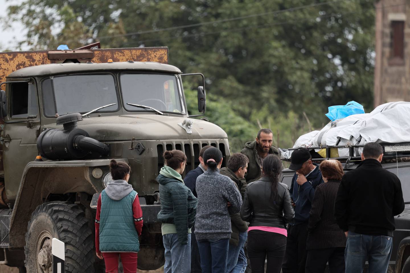 Los refugiados esperan después de cruzar la frontera y llegar a un centro de registro del Ministerio de Asuntos Exteriores de Armenia, cerca de la ciudad fronteriza de Kornidzor,