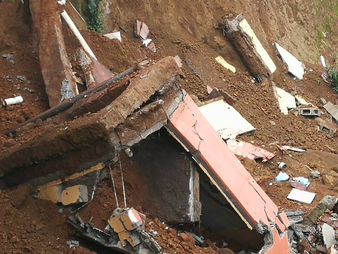 El jueves esta casa desalojada desde el 2020 apareció en el fondo del barranco. Tres dias antes, otra más grande también colapso y se vino desde el borde del deslizamiento en Valladolid de Desamparados. Foto: Marisol Salguero.