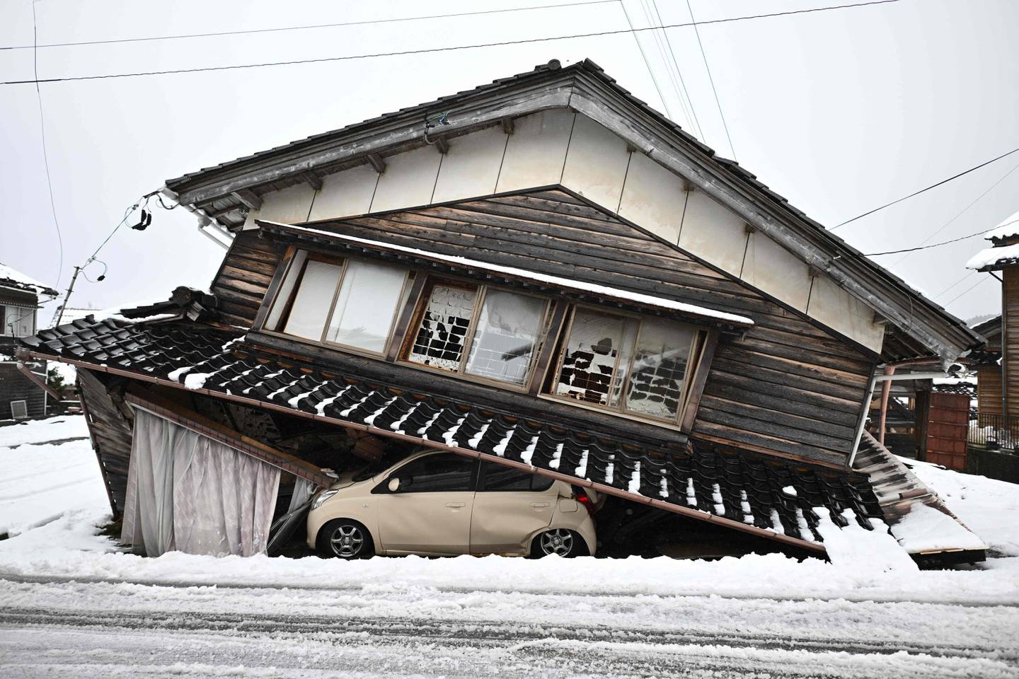 Un automóvil dañado yace debajo de un edificio derrumbado en la ciudad de Shika en el distrito de Hakui, prefectura de Ishikawa después de que un gran terremoto de magnitud 7,5 sacudiera la región de Noto el día de Año Nuevo. (Foto de Philip FONG / AFP)