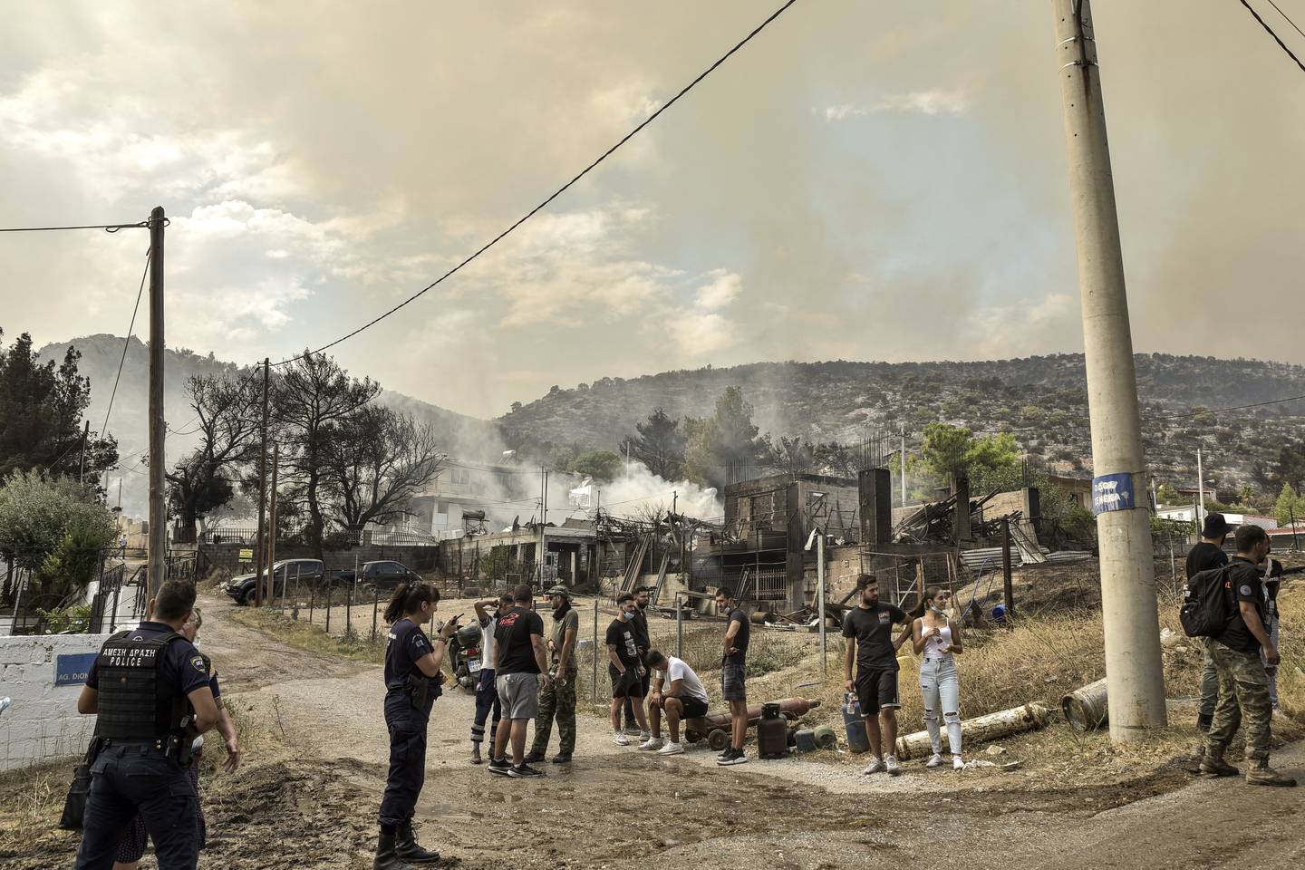 Los residentes locales se reúnen mientras se propaga un incendio forestal en Archanes, al norte de Atenas, los bomberos griegos lucharon por contener incendios incontrolados en todo el país por quinto día, varios de ellos bordeando una zona acre y llena de humo.