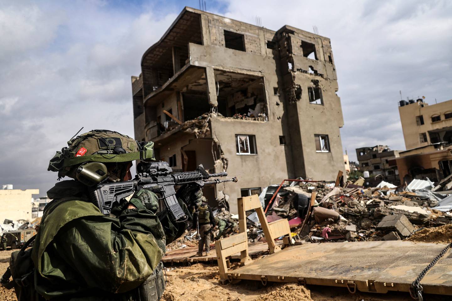 Esta fotografía tomada durante un recorrido mediático organizado por el ejército israelí muestra a un soldado apuntando con su arma frente a un edificio destruido.