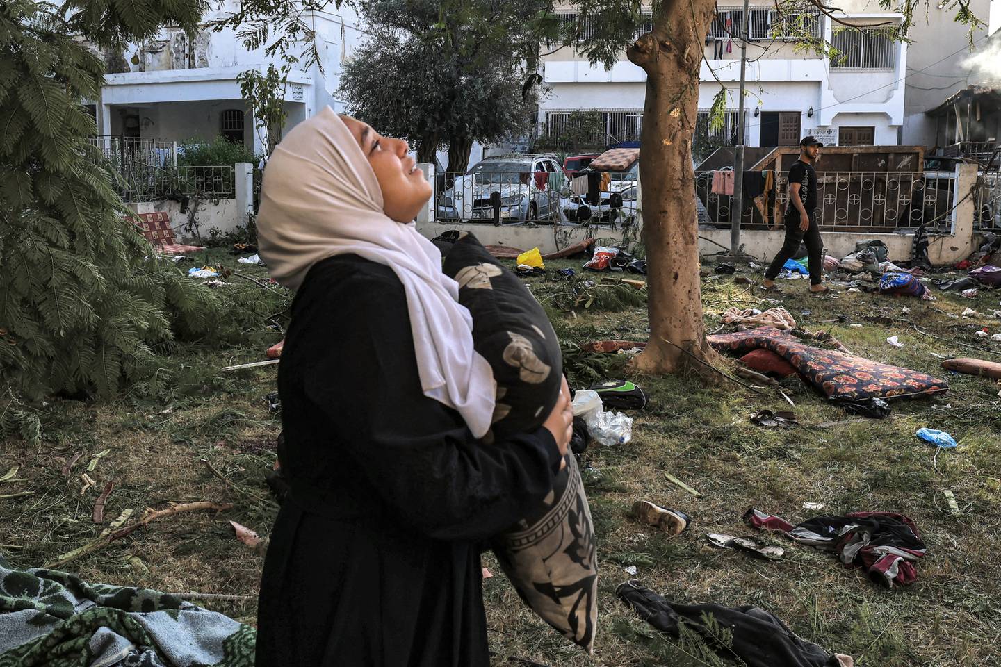 Una mujer reacciona mientras sostiene una almohada y se encuentra entre los escombros frente al hospital Ahli Arab en la ciudad de Gaza