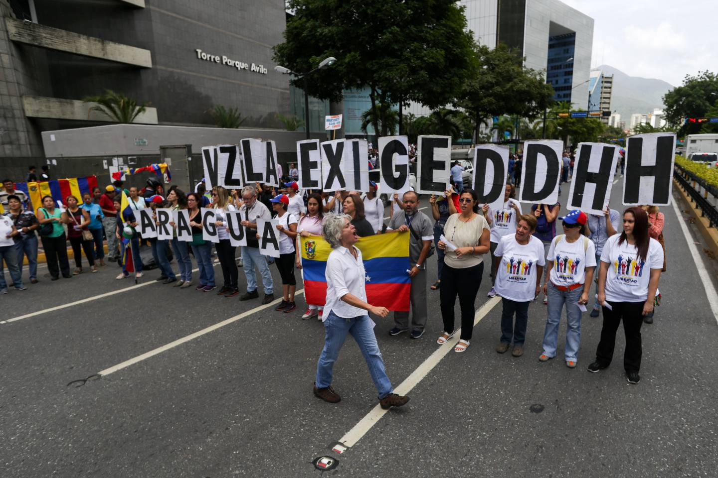 Partidarios de la oposición sostienen carteles con letras que forman las palabras "Venezuela exige Derechos Humanos" mientras se manifiestan frente a la sede del Programa de las Naciones Unidas para el Desarrollo durante la visita de la Alta Comisionada de las Naciones Unidas para los Derechos Humanos, Michelle Bachelet, en Caracas.