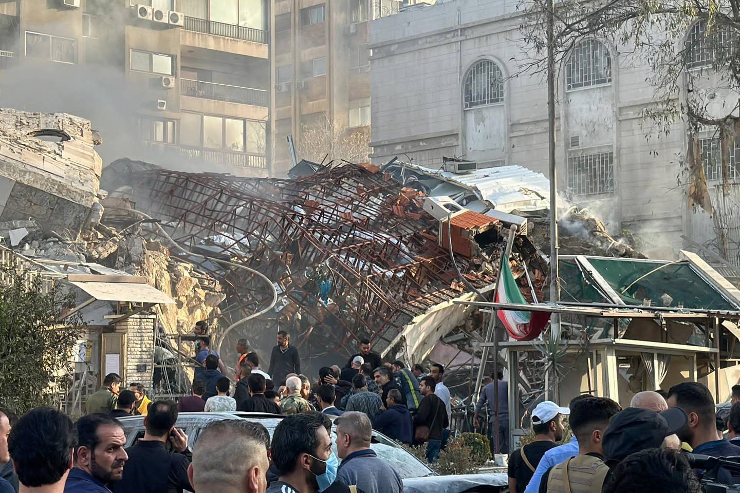 El personal de emergencia y de seguridad se reúne en el lugar de los ataques que alcanzaron un edificio adyacente a la embajada iraní en la capital de Siria, Damasco.