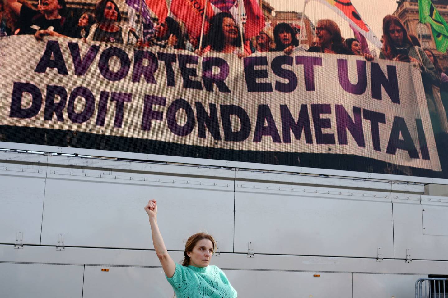 Una mujer aprieta el puño mientras baila frente a una pantalla que muestra un lema que dice 'El aborto es un derecho fundamental' en la Place du Trocadero de París.