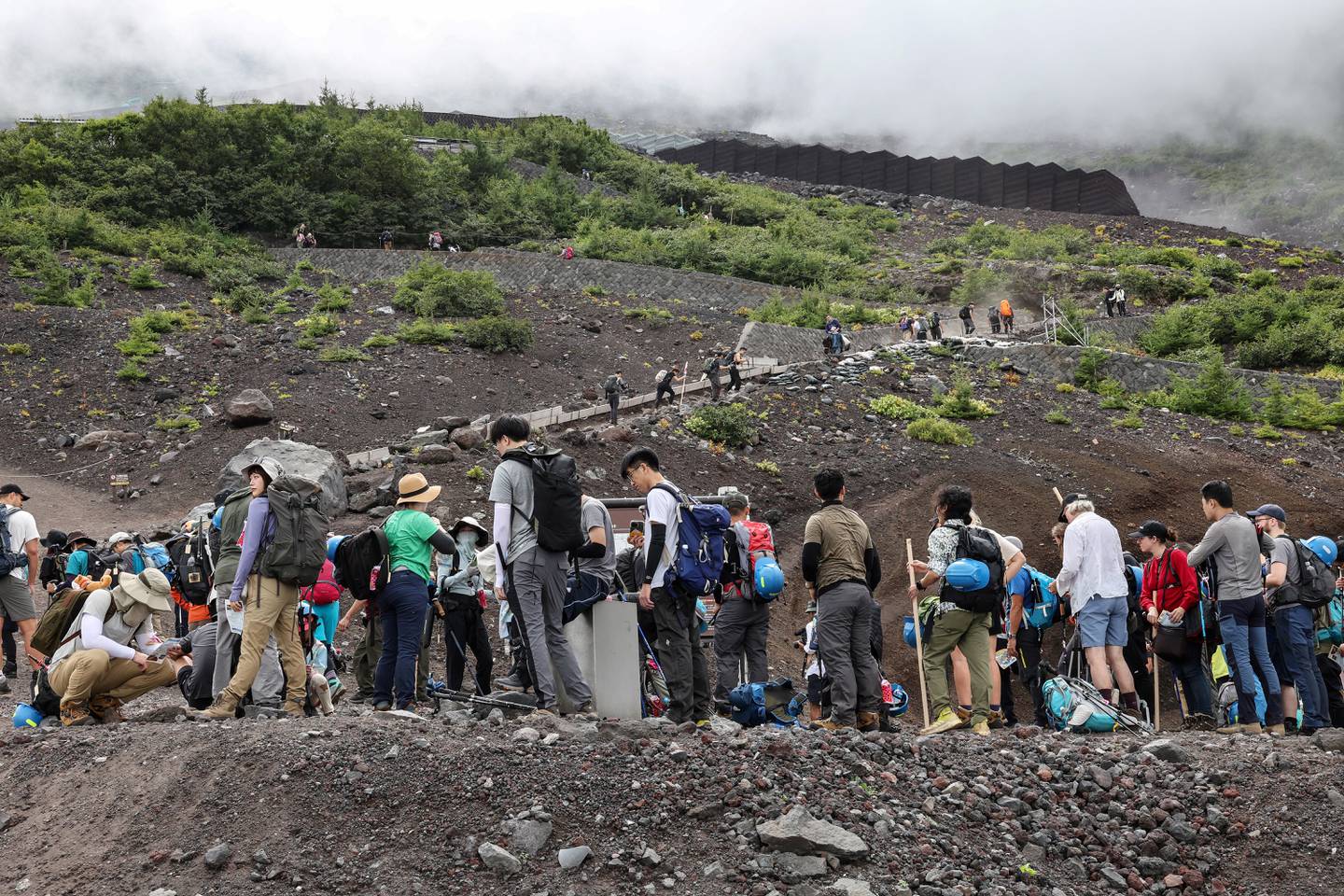 Esta foto tomada el 31 de agosto de 2023 muestra a los visitantes escalando las laderas del Monte Fuji, el pico más alto de Japón con 3.776 metros (12.388 pies). Con sus millones de visitantes cada año y los autobuses, camiones de suministros, tiendas de fideos e imanes para nevera, el Monte Fuji ya no es el lugar de peregrinación tranquilo y lleno de naturaleza que alguna vez fue. (Foto de Mathias CENA / AFP) / PARA IR CON Japón-ocio-ambiente,FOCUS por Mathias CENA