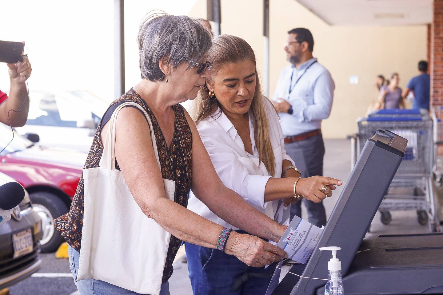 20/01/2024. Mayela Jiménez Vega (de lentes), de 74 años, fue la primera que simuló el voto electrónico en Sabanilla, este sábado 2 de enero, guiada por una funcionaria del TSE. Foto: Lilly Arce.