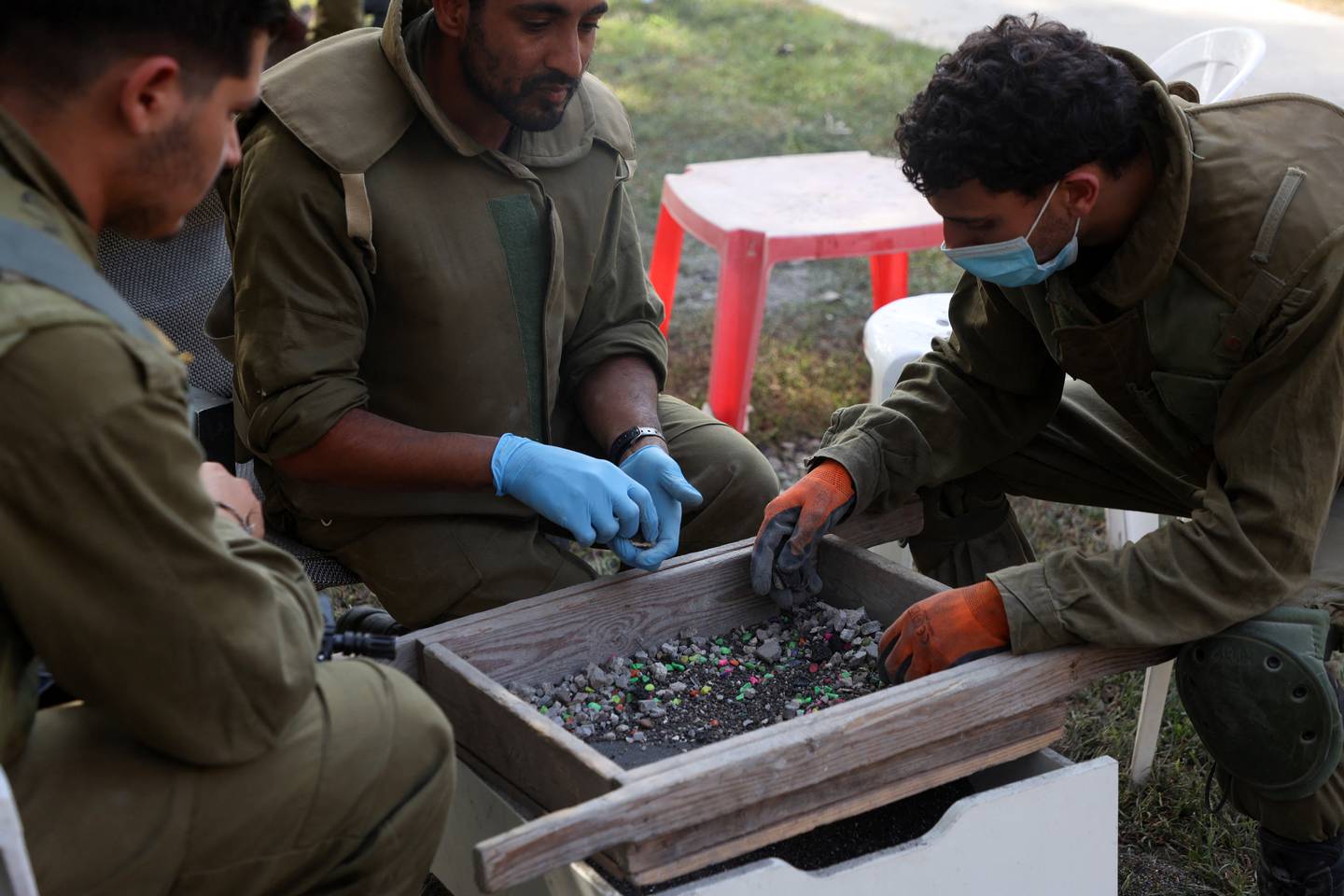 Los soldados israelíes ayudan a los arqueólogos de la Autoridad de Antigüedades de Israel a examinar las cenizas de las viviendas incendiadas dentro del Kibbutz Nir Oz, en el sur de Israel, para identificar a los residentes que desaparecieron durante el ataque del 7 de octubre.