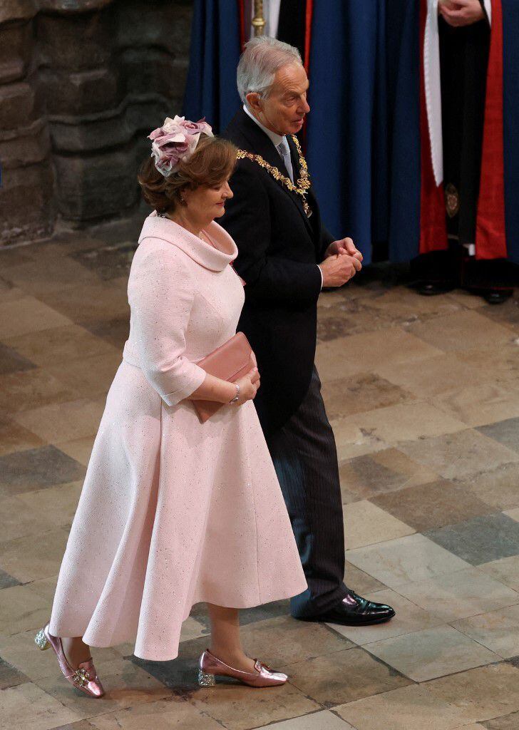 Cherie Blair, esposa del ex primer ministro británico Tony Blair, también escogió el rosa para su vestido, pero en una tonalidad más clara. La mujer acompañó su atuendo, de corta línea A, con unos zapatos brillantes y una cartera de las mismas tonalidades.
En su cabeza lució un adorno de rosas blancas y lilas.  
