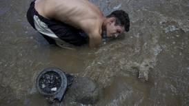 Hambre empuja a buscar algo valioso en aguas de un río muy contaminado en Caracas
