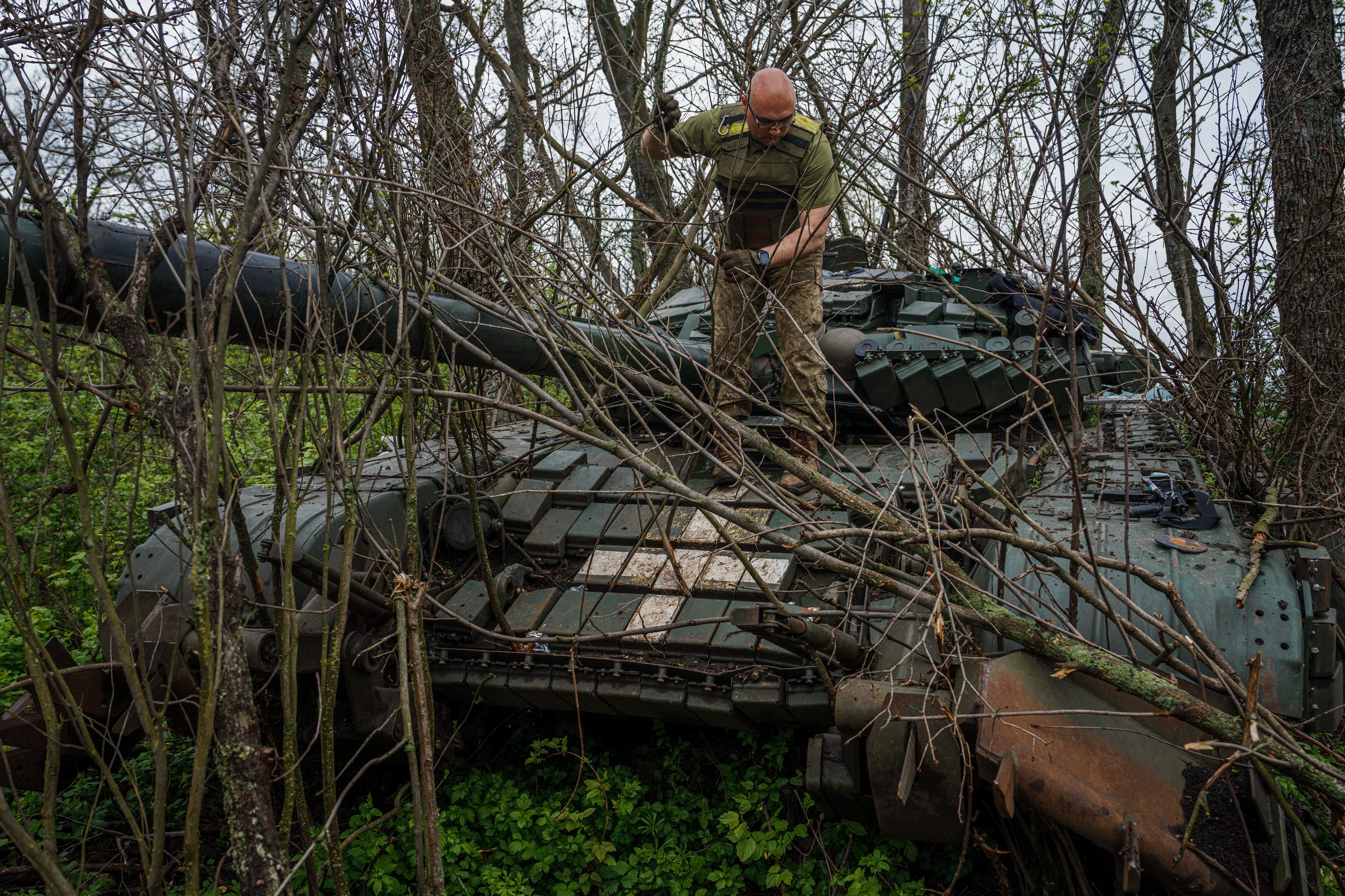 Un militar ucraniano coloca ramas en un tanque, en una posición cerca de la ciudad de primera línea de Bakhmut, región de Donetsk, en medio de la invasión rusa de Ucrania.