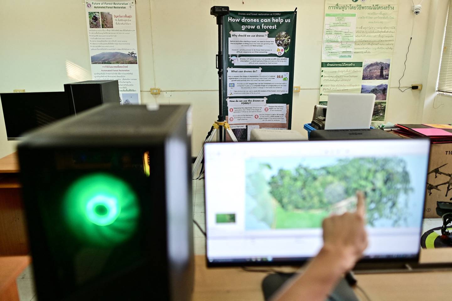 Oficial de investigación de campo de la Unidad de Investigación de Restauración Forestal (FORRU) de la Universidad de Chiang Mai, Worayut Takaew, apuntando a una pantalla de computadora mientras crea un modelo 3D de imágenes superpuestas tomadas con su dron.