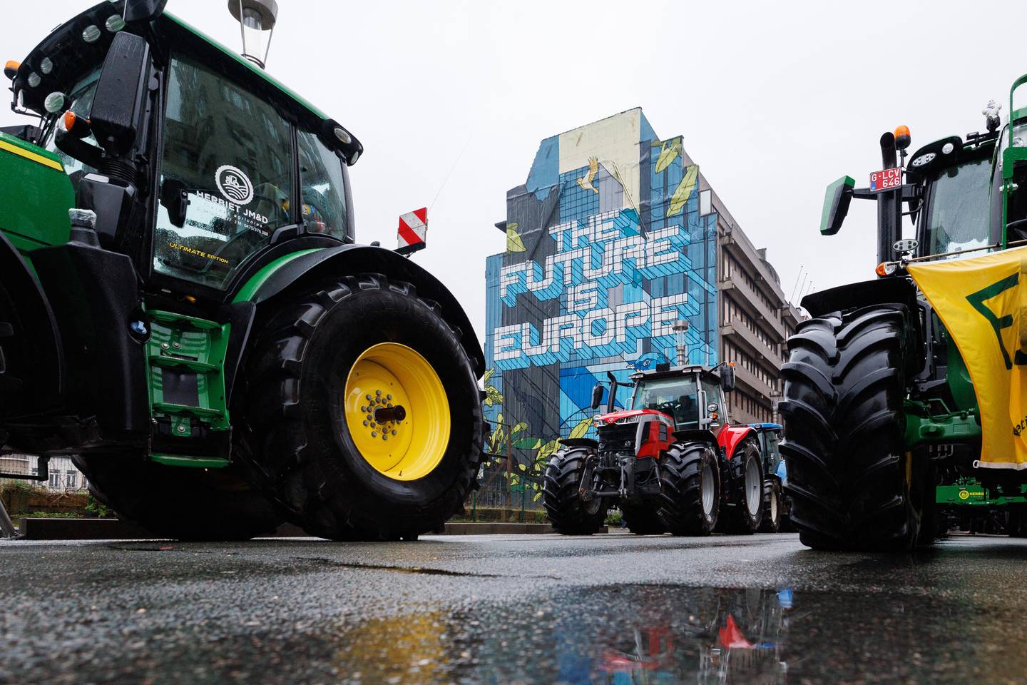 Los tractores están estacionados cerca de un edificio con un mural que dice 'El futuro es Europa' durante una protesta convocada por las organizaciones de agricultores.