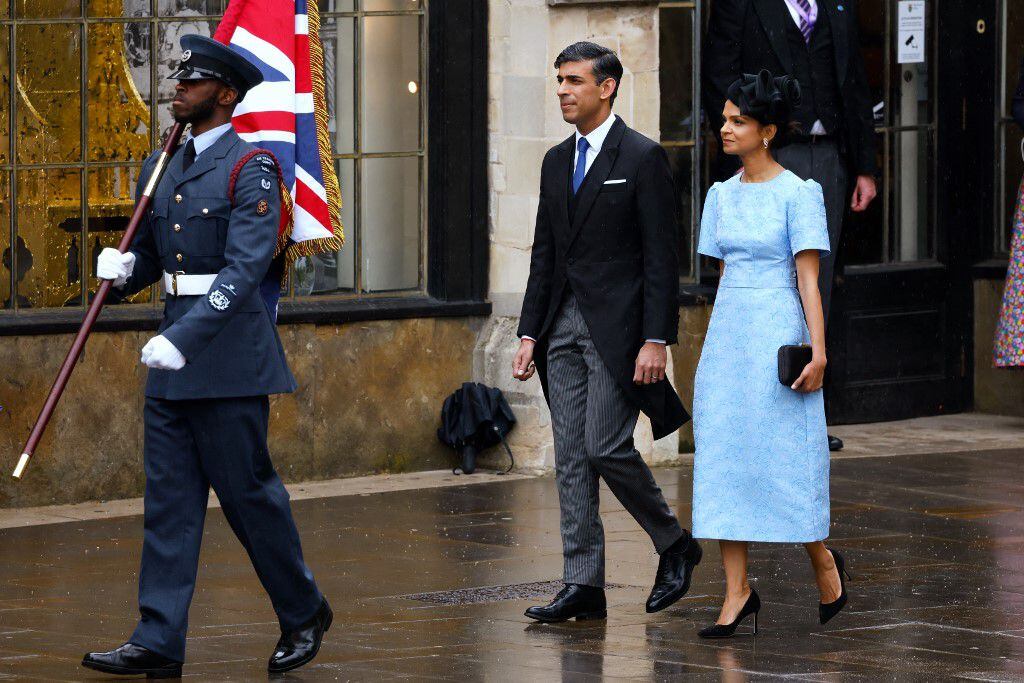 La multimillonaria heredera Akshata, esposa del primer ministro británico, escogió un vestido celeste claro con mangas farol, que acompañó con un tocado negro a juego con los zapatos. 