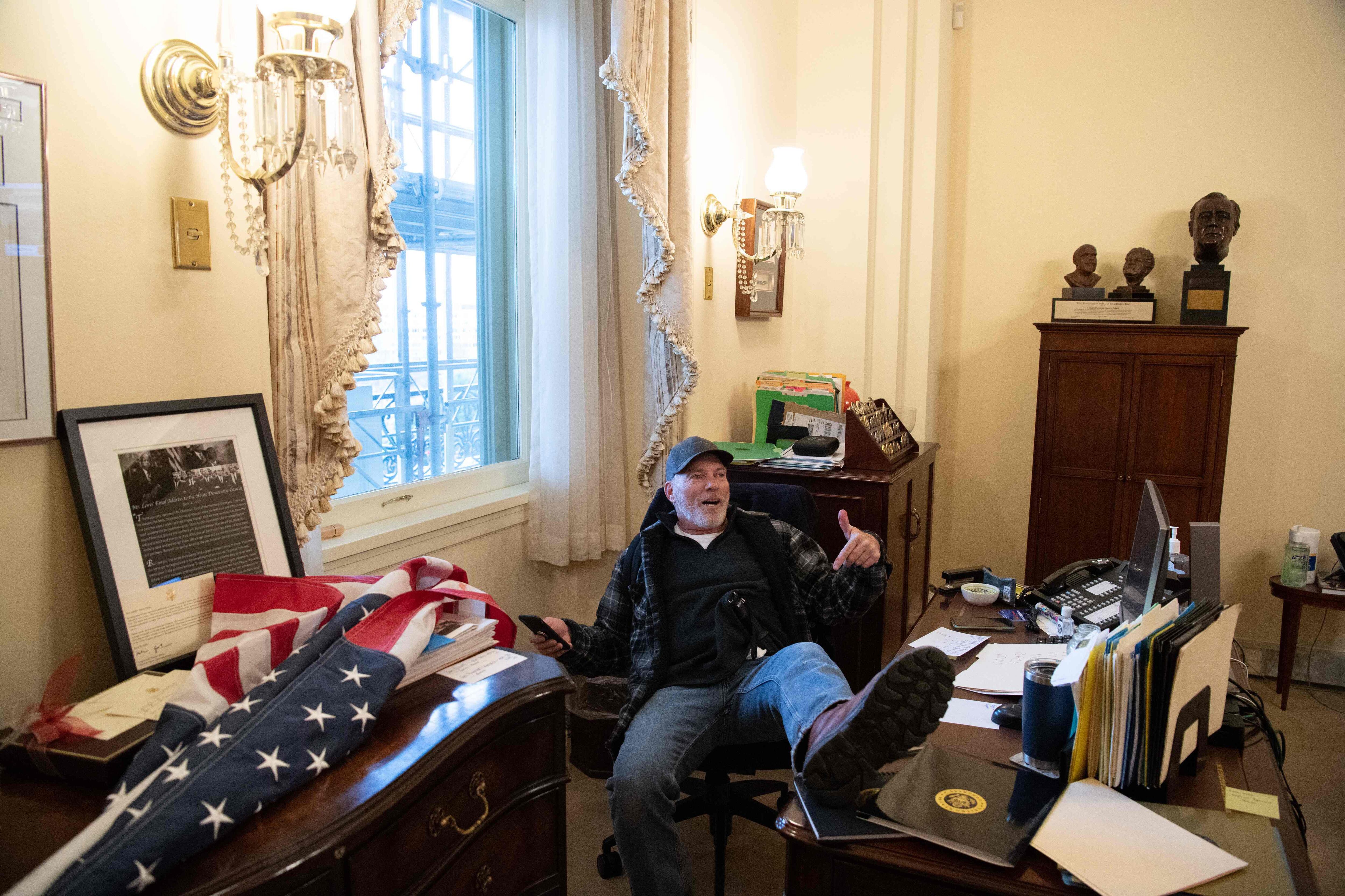 Un partidario del presidente de los Estados Unidos, Donald Trump, se sentó dentro de la oficina de la presidenta de la Cámara de Representantes de los Estados Unidos, Nancy Pelosi, mientras protesta dentro del Capitolio de los Estados Unidos en Washington, DC, el 6 de enero de 2021.