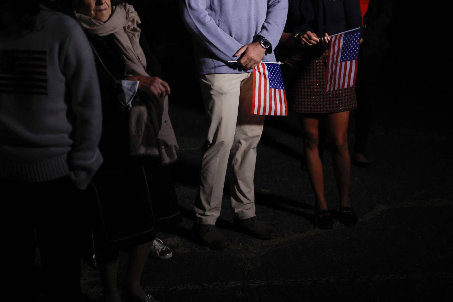 Familiares con banderas estadounidenses esperan para saludar a los detenidos estadounidenses liberados en un acuerdo de intercambio de prisioneros entre Estados Unidos e Irán al llegar al aeródromo del ejército de Davison en Fort Belvoir