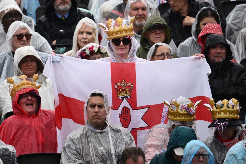 Con una bandera de Irlanda del Norte, una corona y unos lentes, esta seguidora de la monarquía esperó para ver a su nuevo rey y reina consorte. 