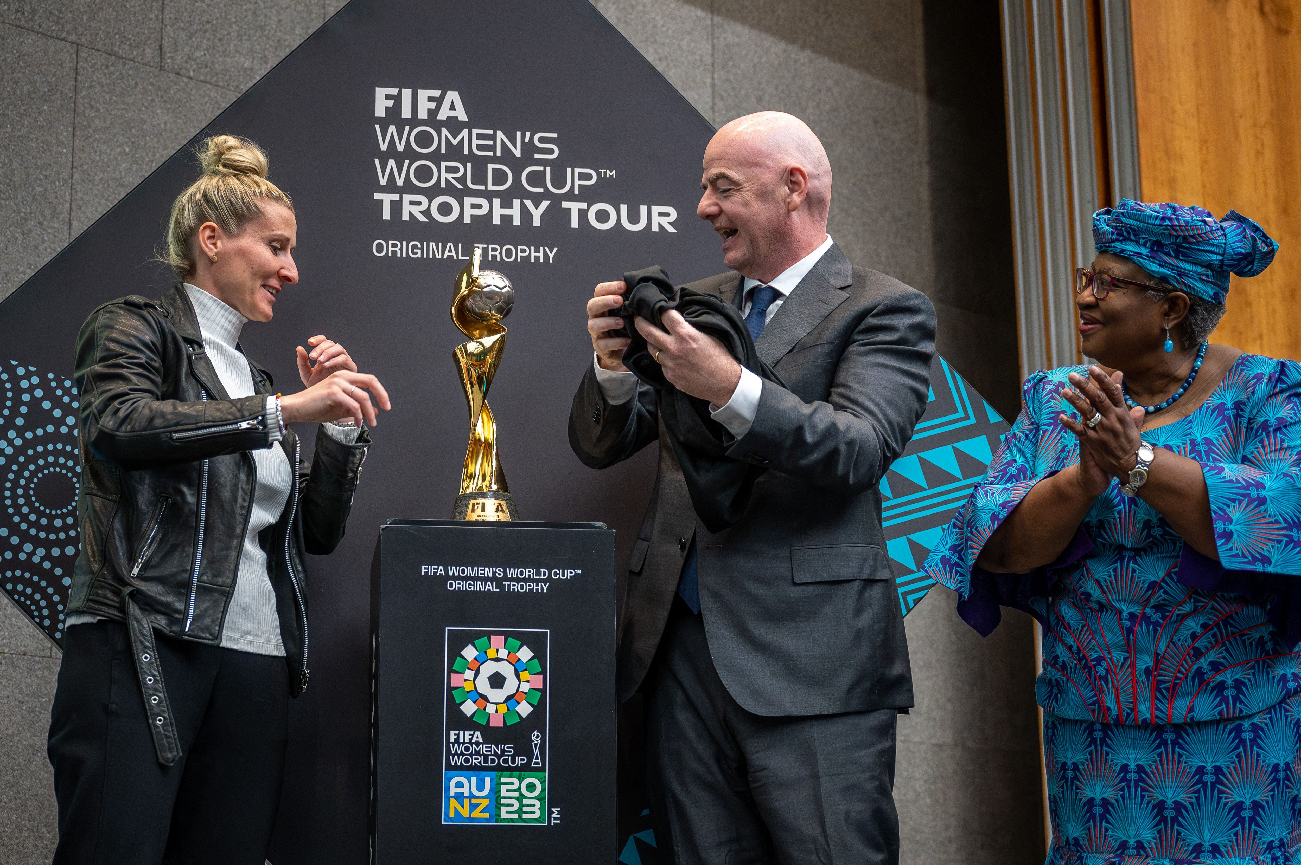 La delantera alemana Anja Mittag (izquierda), el presidente de la FIFA, Gianni Infantino, y la directora general de la Organización Mundial del Comercio (OMC), Ngozi Okonjo-Iweala, presentan el trofeo de la Copa Mundial Femenina de la FIFA durante el evento 