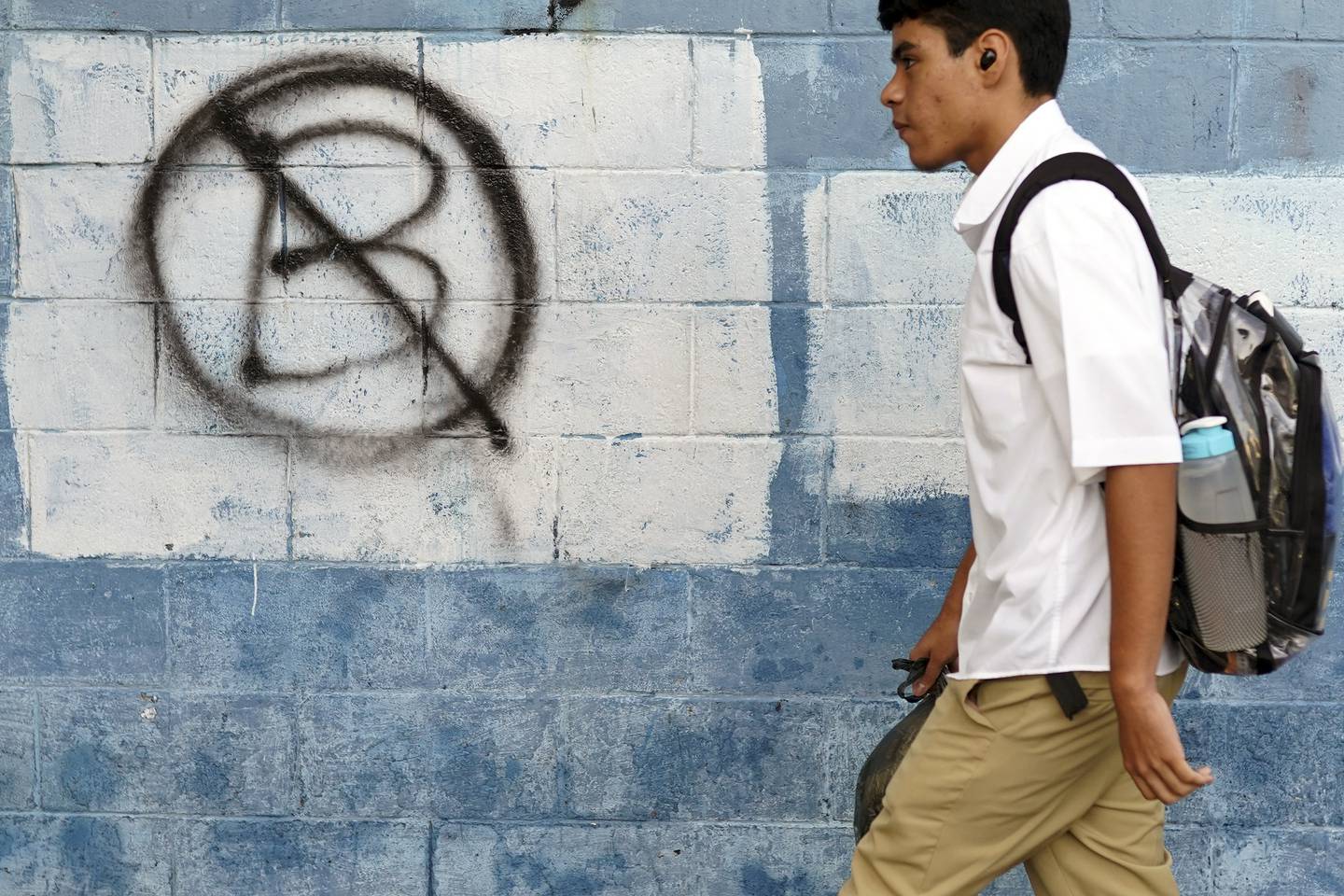 Un estudiante pasa junto a un muro pintado con un símbolo de protesta anti-bitcoin