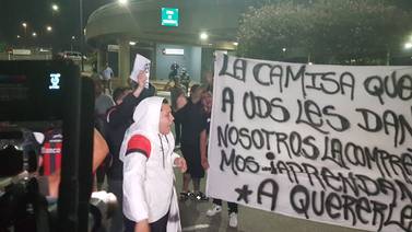 Aficionados de Alajuelense reciben al equipo con reproches, mantas y monedas