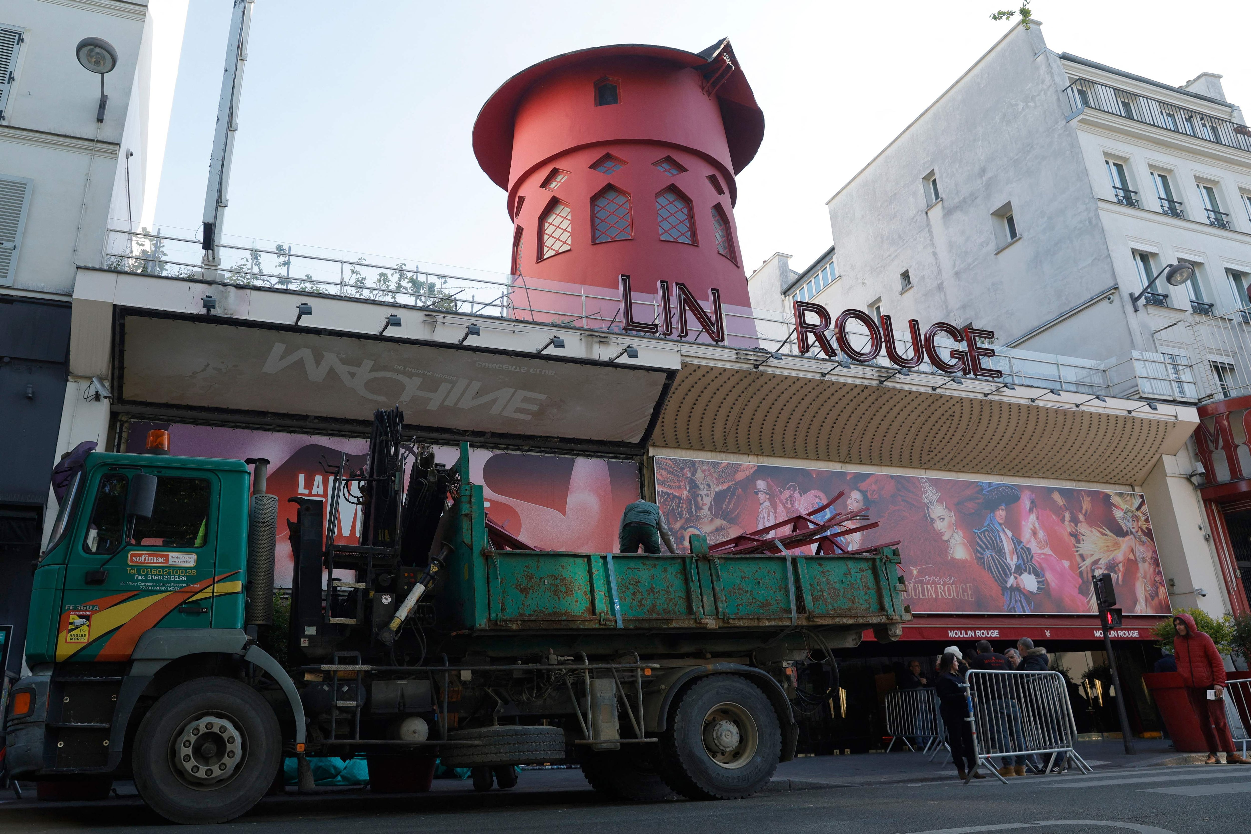 Los trabajadores cargan las aspas del molino de viento del Moulin Rouge que se derrumbó durante la noche sin causar heridos, dijeron los bomberos a la AFP, en París, el 25 de abril de 2024. (Foto de Geoffroy VAN DER HASSELT / AFP).