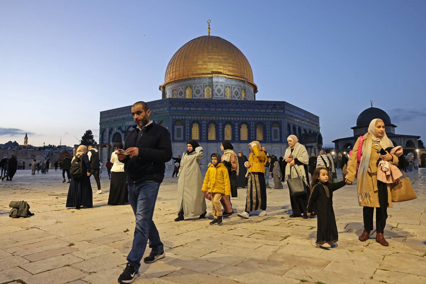 La gente pasa junto a la Cúpula de la Roca en el recinto de la mezquita de Al-Aqsa antes del inicio del mes sagrado de ayuno islámico del Ramadán, en la Ciudad Vieja de Jerusalén.