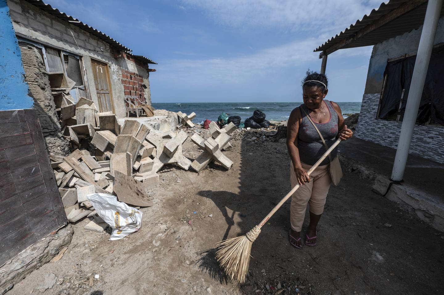 Una mujer barre fuera de su casa afectada por el aumento del nivel del mar en la isla Tierra Bomba, Cartagena.