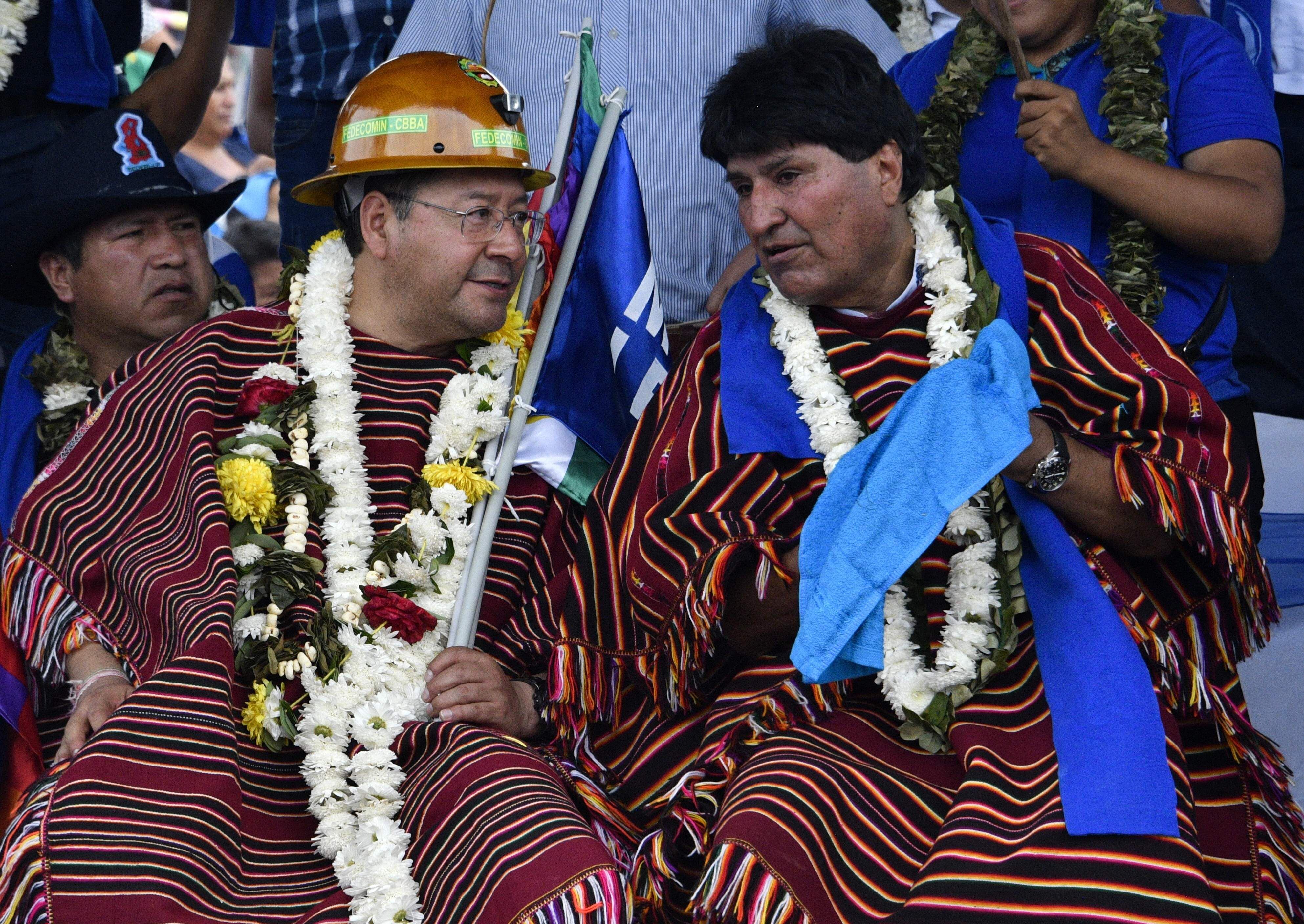 El presidente de Bolivia, Luis Arce (izquierda) y el expresidente (2006-2019) Evo Morales, con guirnaldas de flores y hojas de coca, conversan durante una reunión política para conmemorar el 28º aniversario del partido gobernante Movimiento Al Socialismo (MAS). , en Ivirgarzama, en la provincia rural cocalera de Chapare, departamento de Cochabamba.
