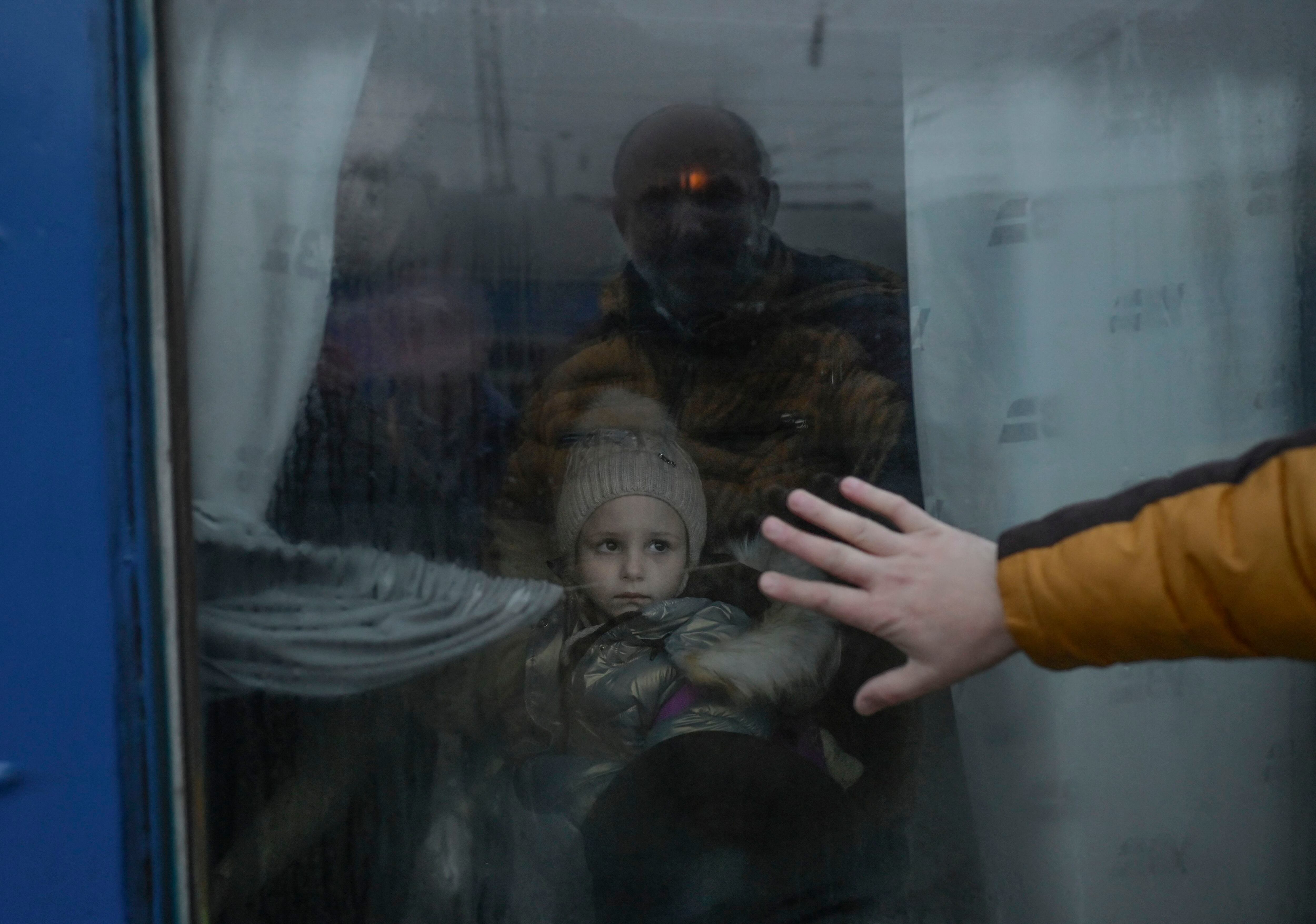 El 7 de marzo de 2022, un padre pone su mano en la ventana mientras se despide de su hija frente a un tren de evacuación en la estación central de trenes en Odessa.