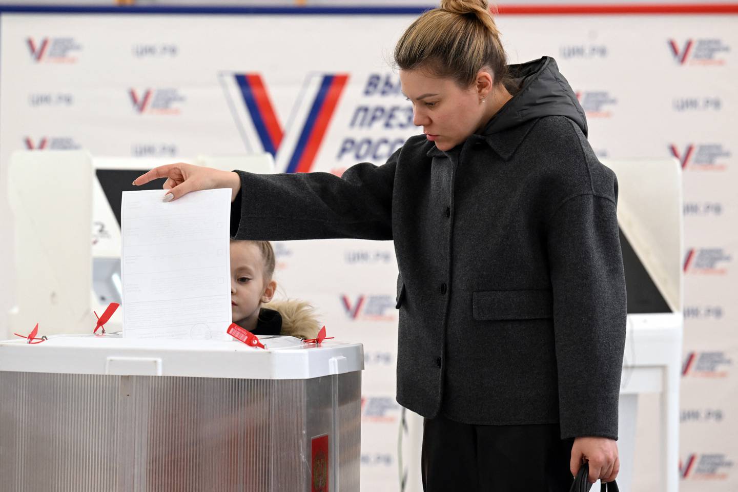 Una mujer con su hijo vota en las elecciones presidenciales de Rusia.